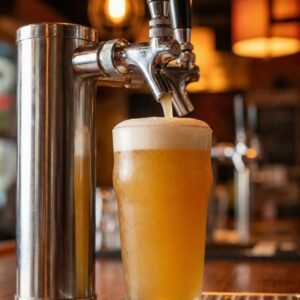 A fresh pint of local craft IPA being poured from a tap at a bar.